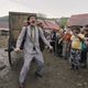Sacha Baron Cohen as Borat Sagdiyev in Borat Subsequent Moviefilm, walking through a village while pulling a cart